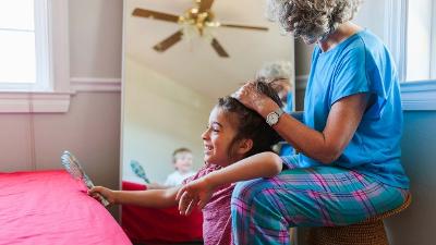 Woman in PJs brushing a young girls hair