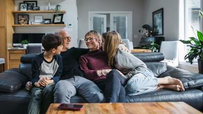 Older couple with two children snuggled on sofa together