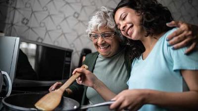 Teenage girl and older lady in kitchen with frying pan