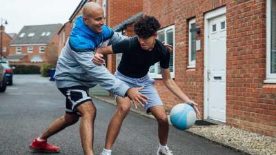 Man and boy playing football in the street