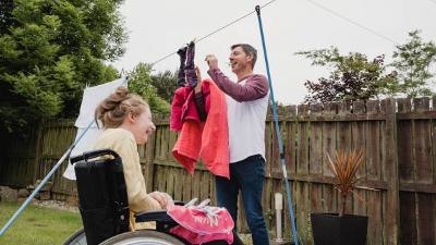 Man pegging out washing and girl in wheelchair